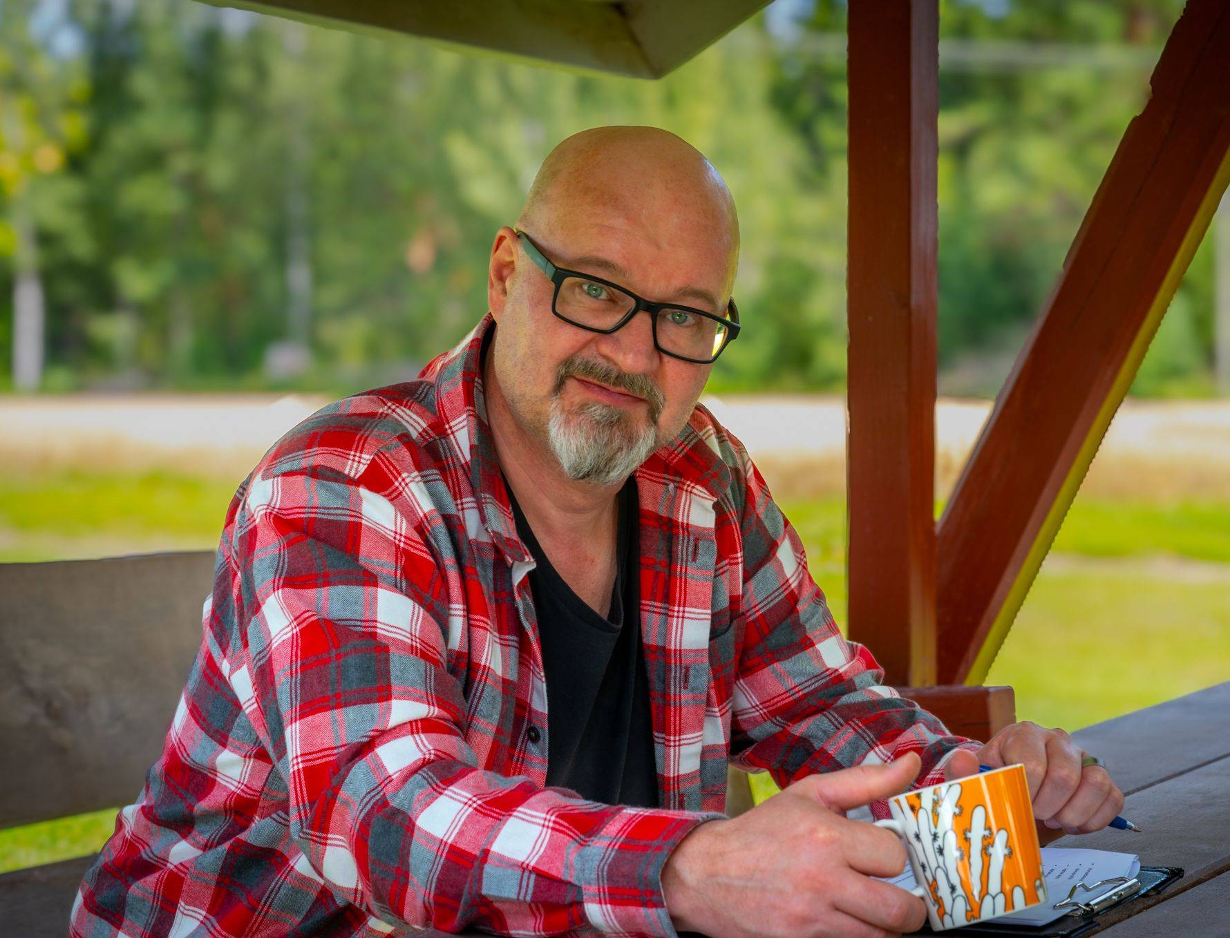 Sami Hilonen mökin laavun pöydän ääressä kahvikuppi kädessä
